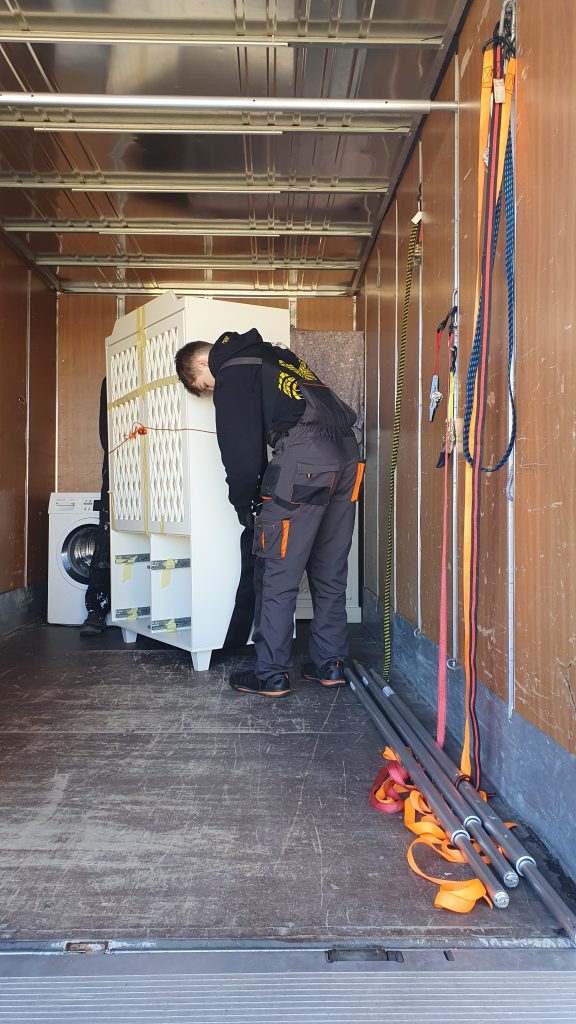 Mitarbeiter von Lünekurier verladen einen Schrank in einen LKW