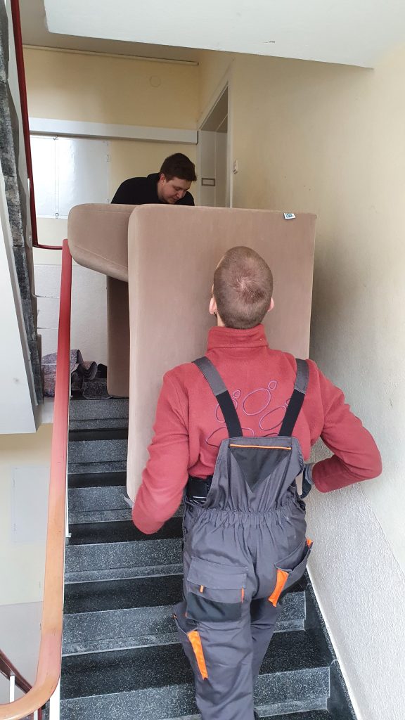 Mitarbeiter von Martens Umzüge tragen ein Sofa durch ein Treppenhaus